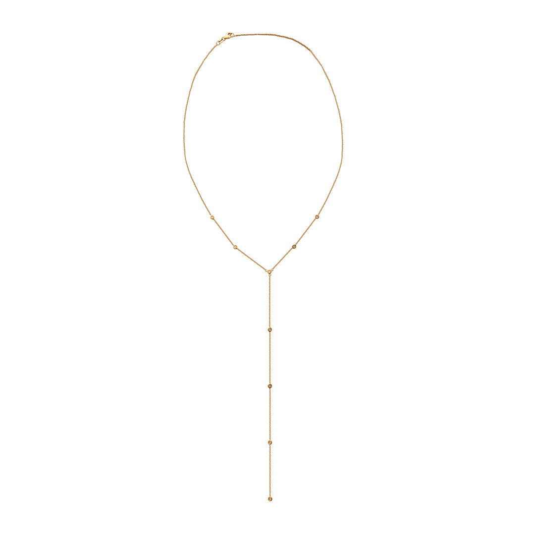 Gold lariat necklace with station set diamonds on a white background