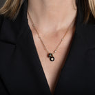 A person wearing a diamond station necklace with numerous beads and charms. 