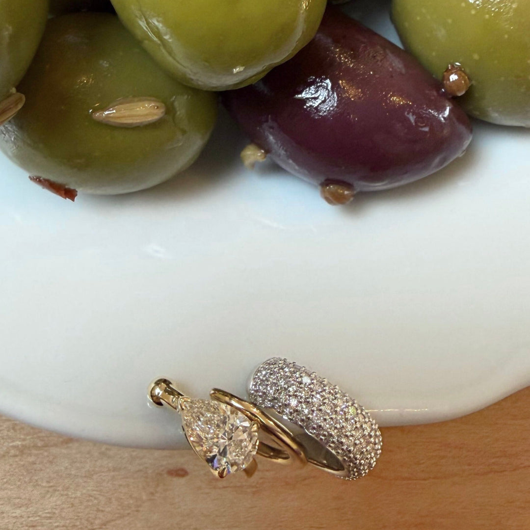 A bowl of olives with three ear cuffs on the edge of the bowl. 