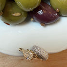 A bowl of olives with three ear cuffs on the edge of the bowl. 