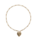 A 14k gold chain with two clasps attached together, holding a heart charm set on a white background. 