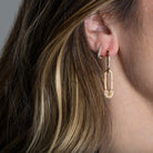 Someone wearing two gold earrings. 