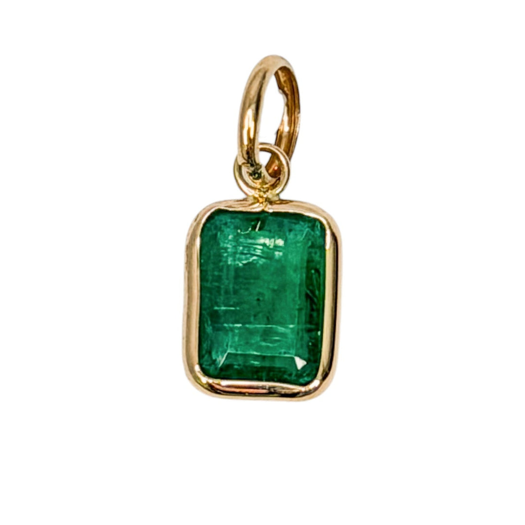 A 14k gold mini pendant with a emerald stone, set on a white background.