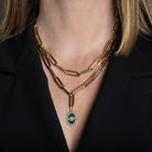 A person wearing two 14k gold chunky paperclip chains, with one of them featuring a malachite pendant. 
