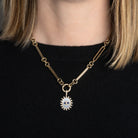 A person wearing a gold link necklace with an Evil Eye Mother of Pearl, Lapis and Diamond Pendant. 