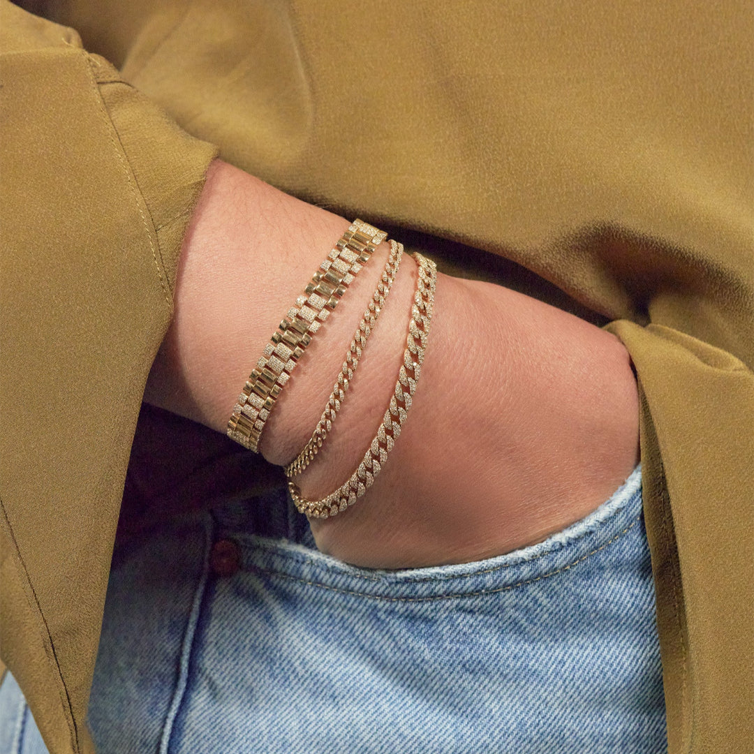 A person wearing three gold and diamond bracelets. 