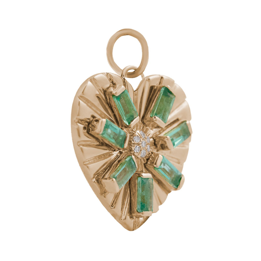 A sideways view of a gold heart pendant with emeralds and diamonds. 