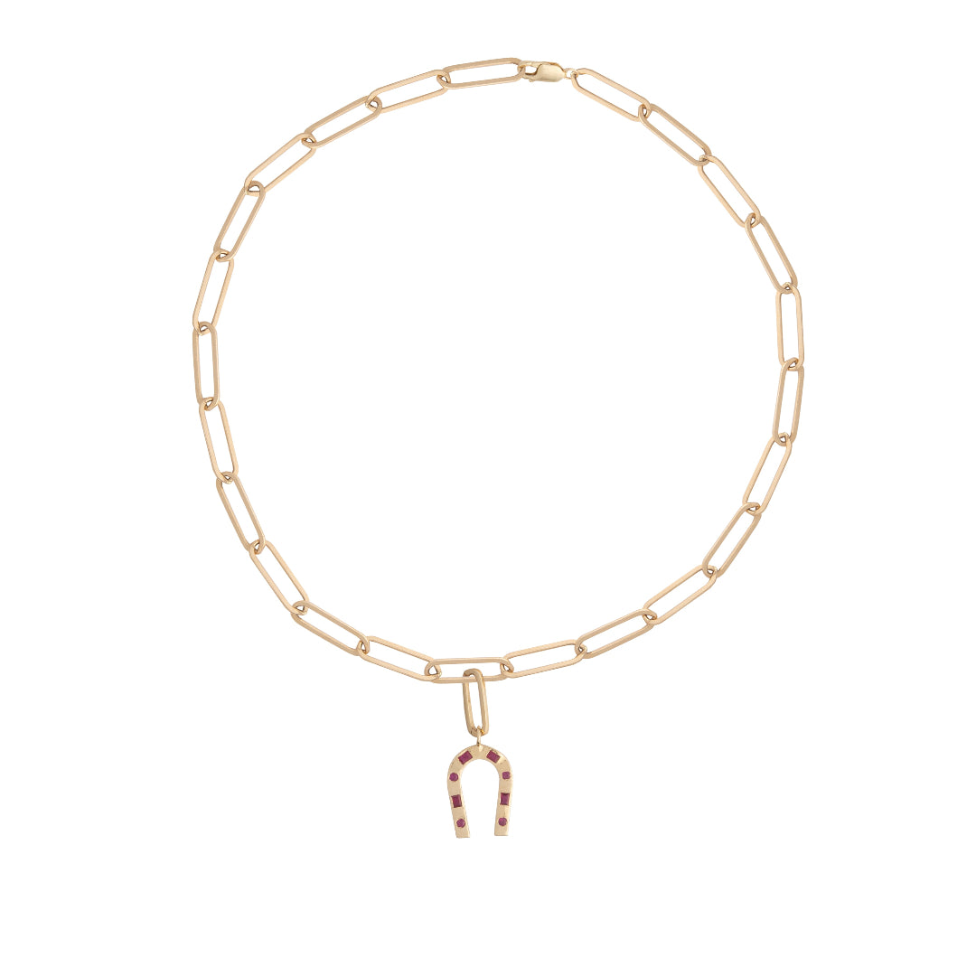 A paperclip chain necklace with a horseshoe-shaped ruby pendant attached. 