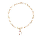 A paperclip chain necklace with a horseshoe-shaped ruby pendant attached. 