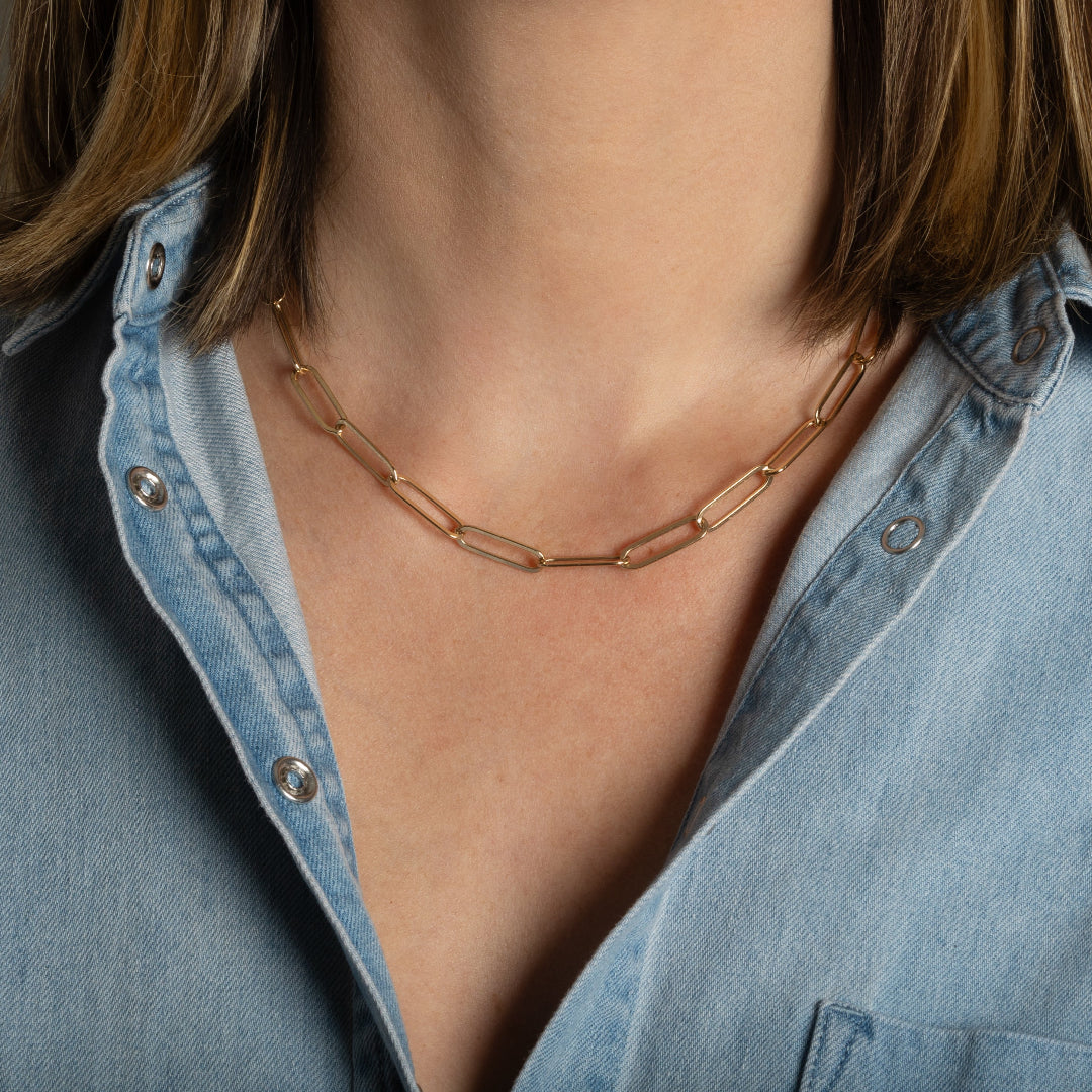 A person wearing a 14k gold paperclip chain necklace. 