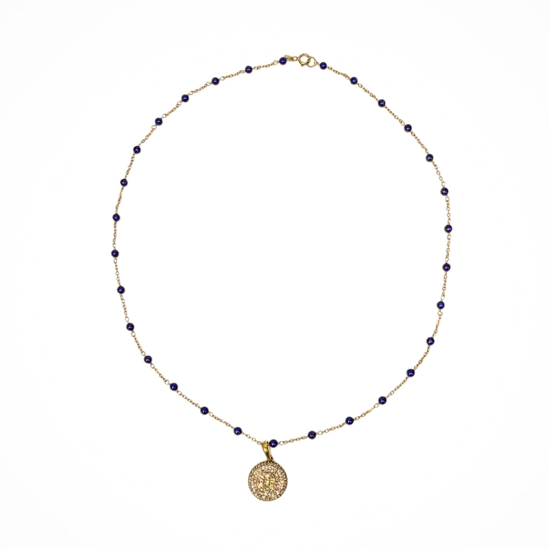 A 14k gold station necklace with lapis beads and pavé diamond pendant on a white background. 