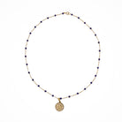 A 14k gold station necklace with lapis beads and pavé diamond pendant on a white background. 