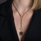 A person wearing a paperclip lariat necklace with a gold LOVE pendant attached. 