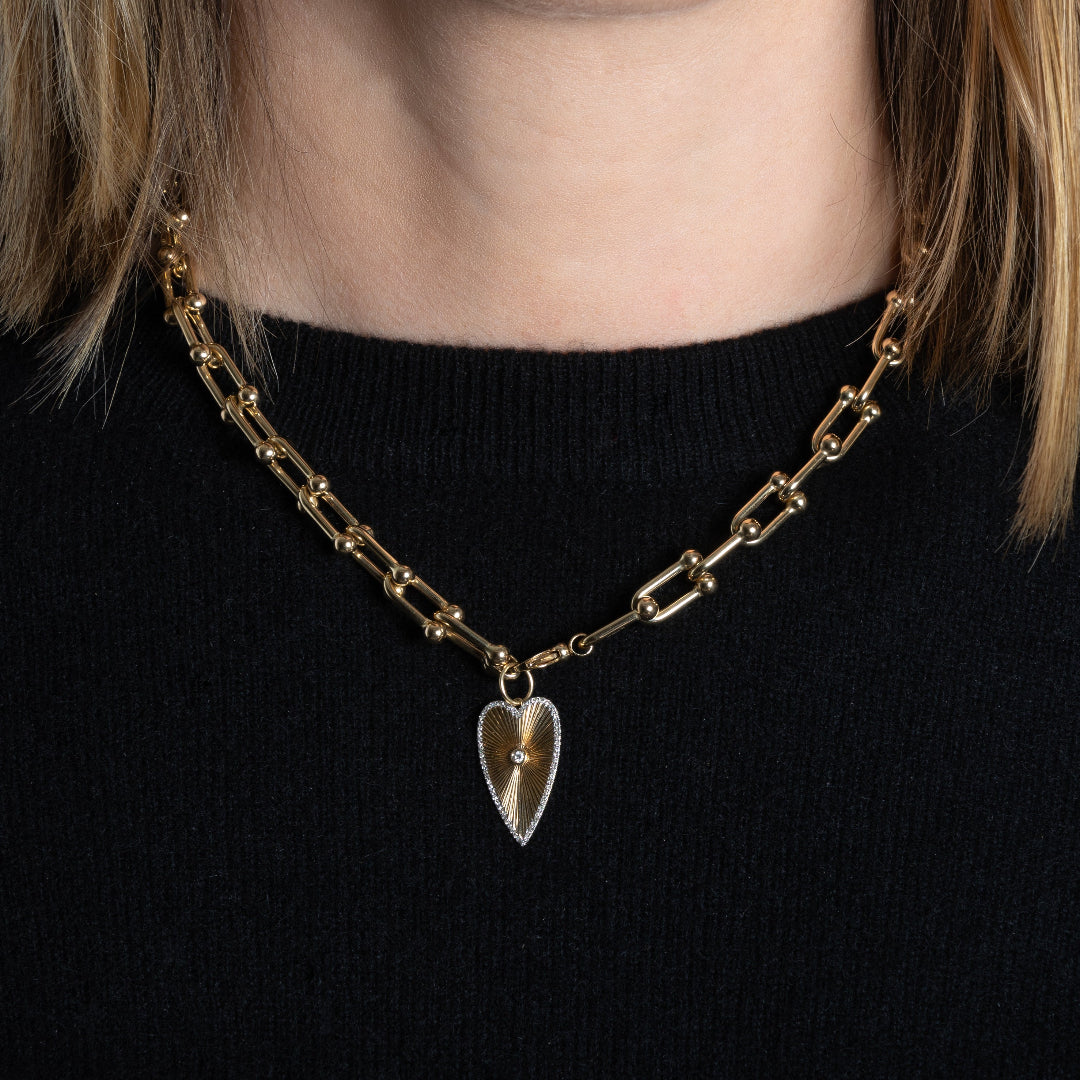 A gold chunky u-link chain with a gold Long Heart Sunrays Pendant attached. 