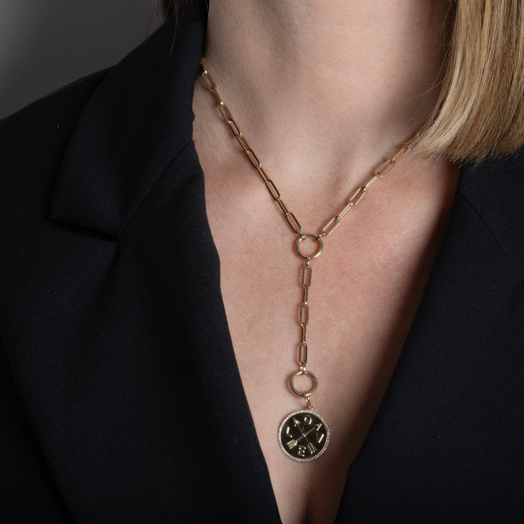 A person wearing a paperclip chain necklace with a gold pendant. 