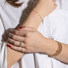 Close-up of a person's wrist and hand wearing gold jewelry on a white background