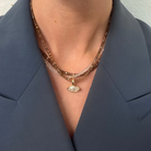 A person wearing a blue blazer and three gemstone necklaces with a bezel-set marquise pendant. 