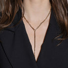 Gold chain necklace lariat necklace worn by a person with a black blazer.