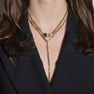 Close-up of a layered gold necklace on a person wearing a black outfit.