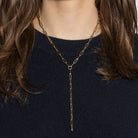 Gold chain necklace worn by a person on a dark background
