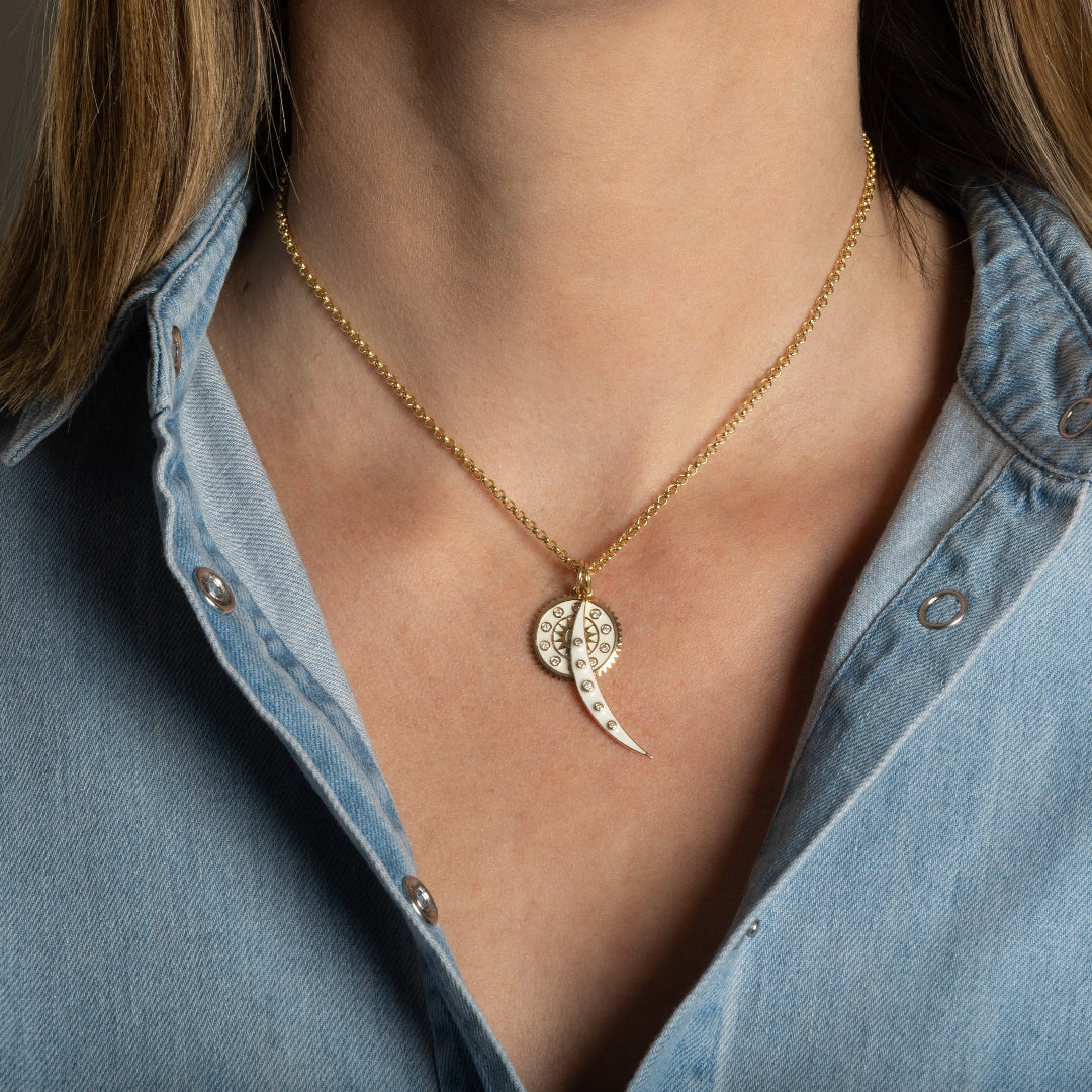 A 14k gold mini rolo chain necklace on a person with two gold and white enamel pendants. 