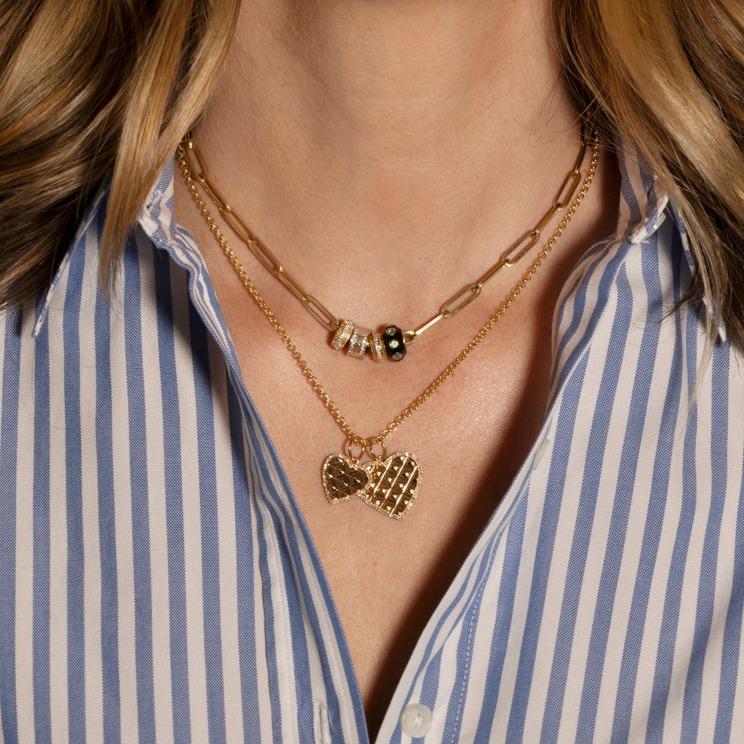 A woman with a striped shirt wearing two gold necklaces. 