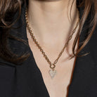 Necklace with a heart-shaped pendant worn by a person with a black blazer on.