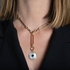 A person wearing a gold link necklace and a Mother of Pearl, Diamond and Black Onyx Pendant attached to the end. 