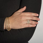 A person wearing three diamond tennis bracelets and three stackable rings. 