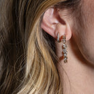Close-up of a person wearing diamond hoop earrings with soft lighting.