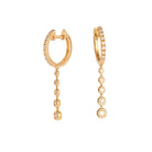 Gold hoop earrings with dangling beads on a white background