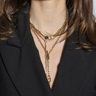 Close-up of a person wearing three gold necklaces with a black background