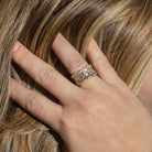 A person pulling their hair back from their face showcasing three stacking diamond band rings of different shaped diamonds set in 14k gold.  