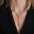 A person wearing a gold paperclip lariat-style necklace. 