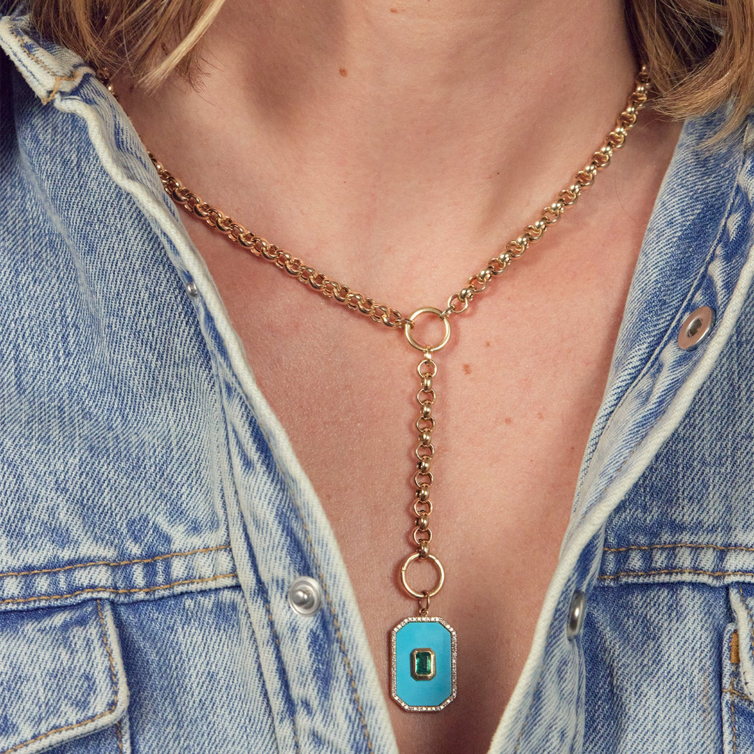 A person wearing a 14k gold rolo lariate chain with a Rectangular Turquoise, Emerald and Diamond Pendant attached. 