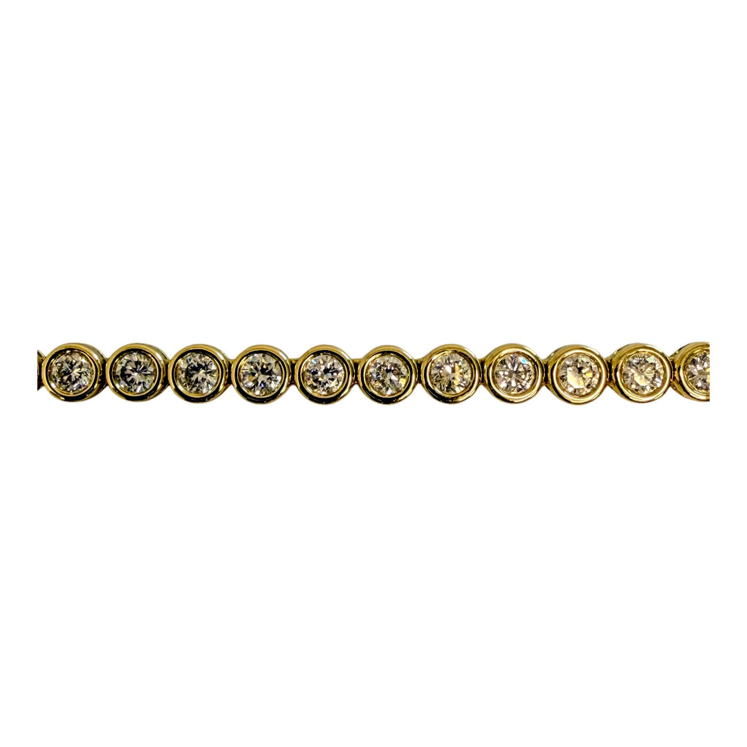 A  close up of a 14k gold round bezel set necklace on a white background. 