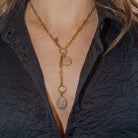 14k gold chain necklace with two pavé diamond pendants worn by a person in a dark textured garment.