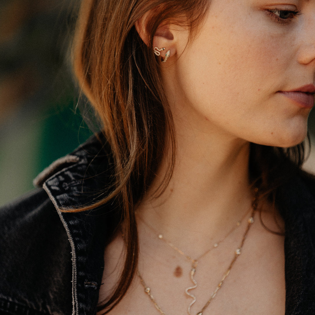 Close-up of a woman wearing gold necklaces and earrings with a blurred background