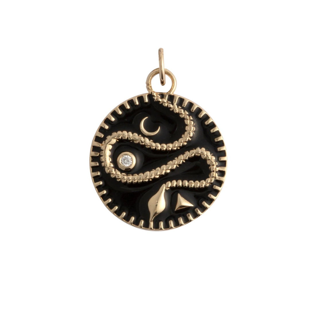 A black enamel pendant set in gold with a serpent and a diamond on a white background. 
