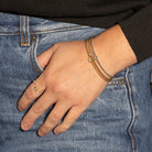 Hand wearing a a stack of bangles and ring on a denim background
