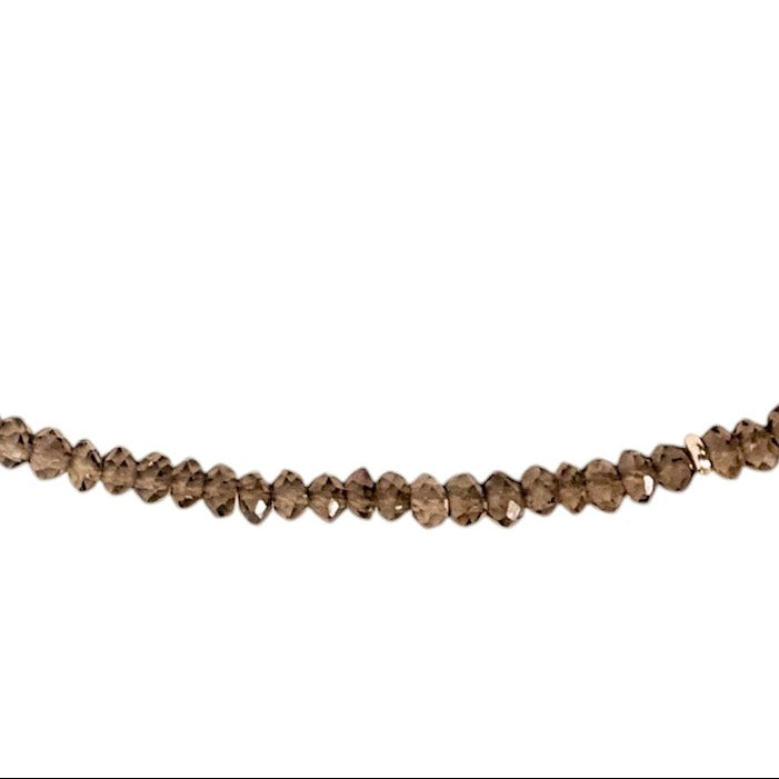 A delicate beaded necklace made of small, faceted snoky quartz beads, arranged in an oval shape on a plain white background.