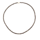 A beaded necklace made of small, faceted snoky quartz beads, arranged in an oval shape on a plain white background.