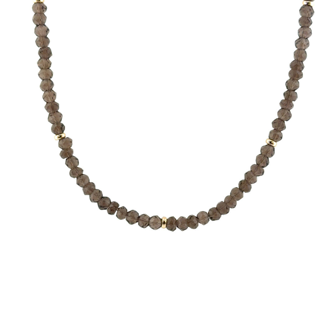A beaded necklace made of small faceted smoky quartz beads with a few small gold spacer beads, shown against a plain white background.