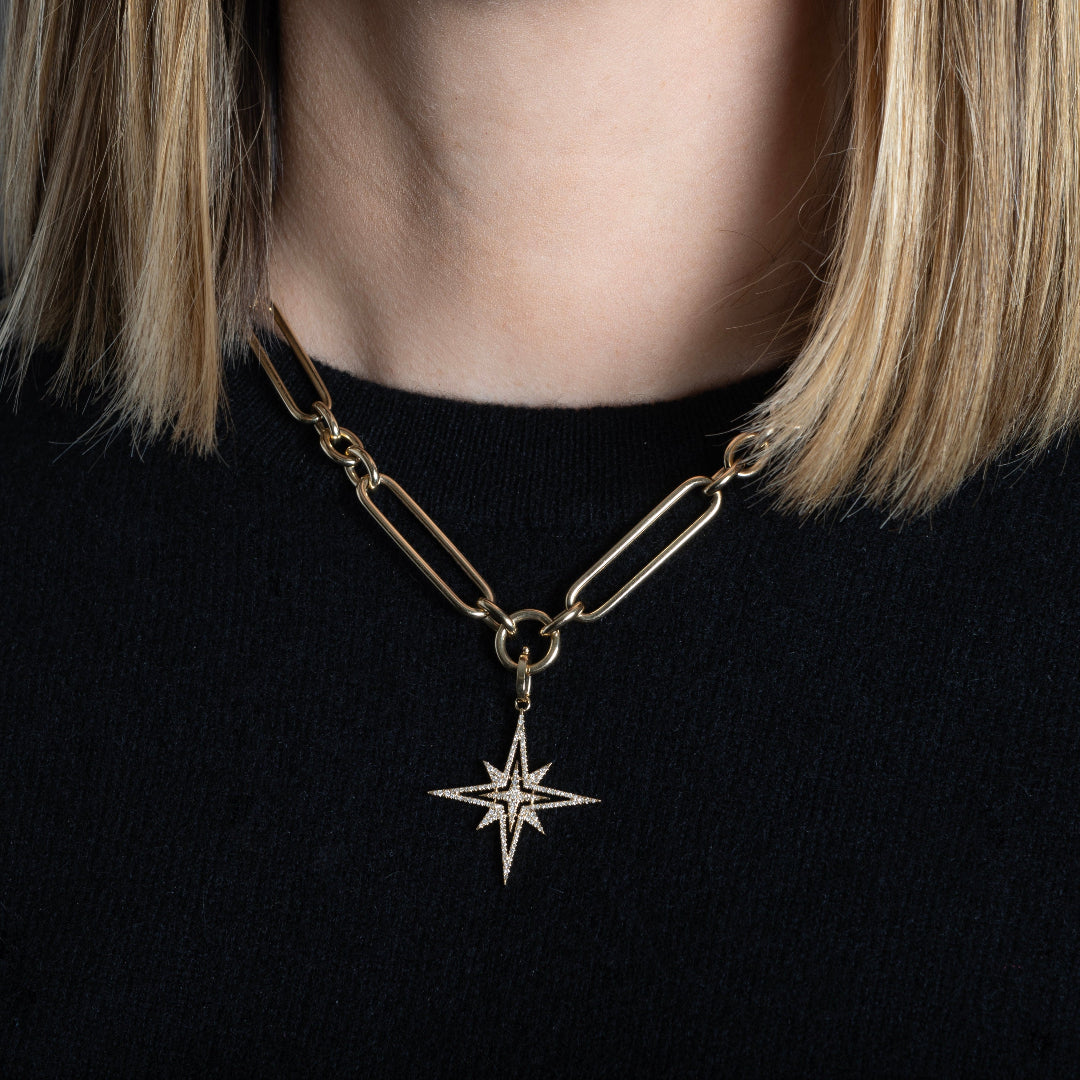 A person wearing a chunky gold chain with a Starburst Diamond Pendant attached. 