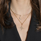 Close-up of a person wearing gold necklaces with star and moon pendants.
