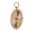A sideways shot of a gold circular pendant with diamonds and a turquoise center. 
