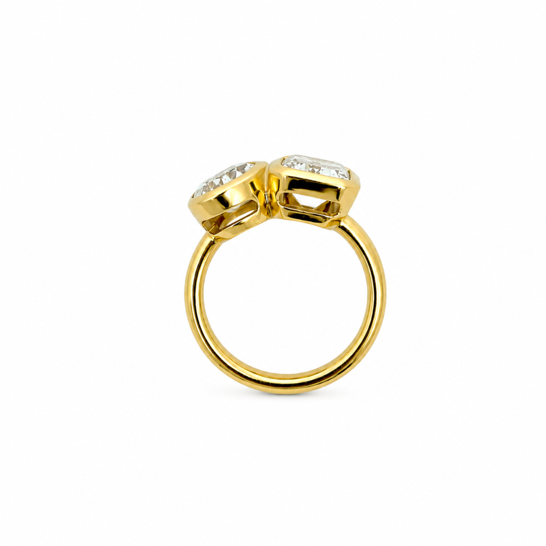 A close-up of a person's hand wearing a 14k yellow gold  bezel set moi et toi ring, resting on a cream and rust-khaki knit sweater.