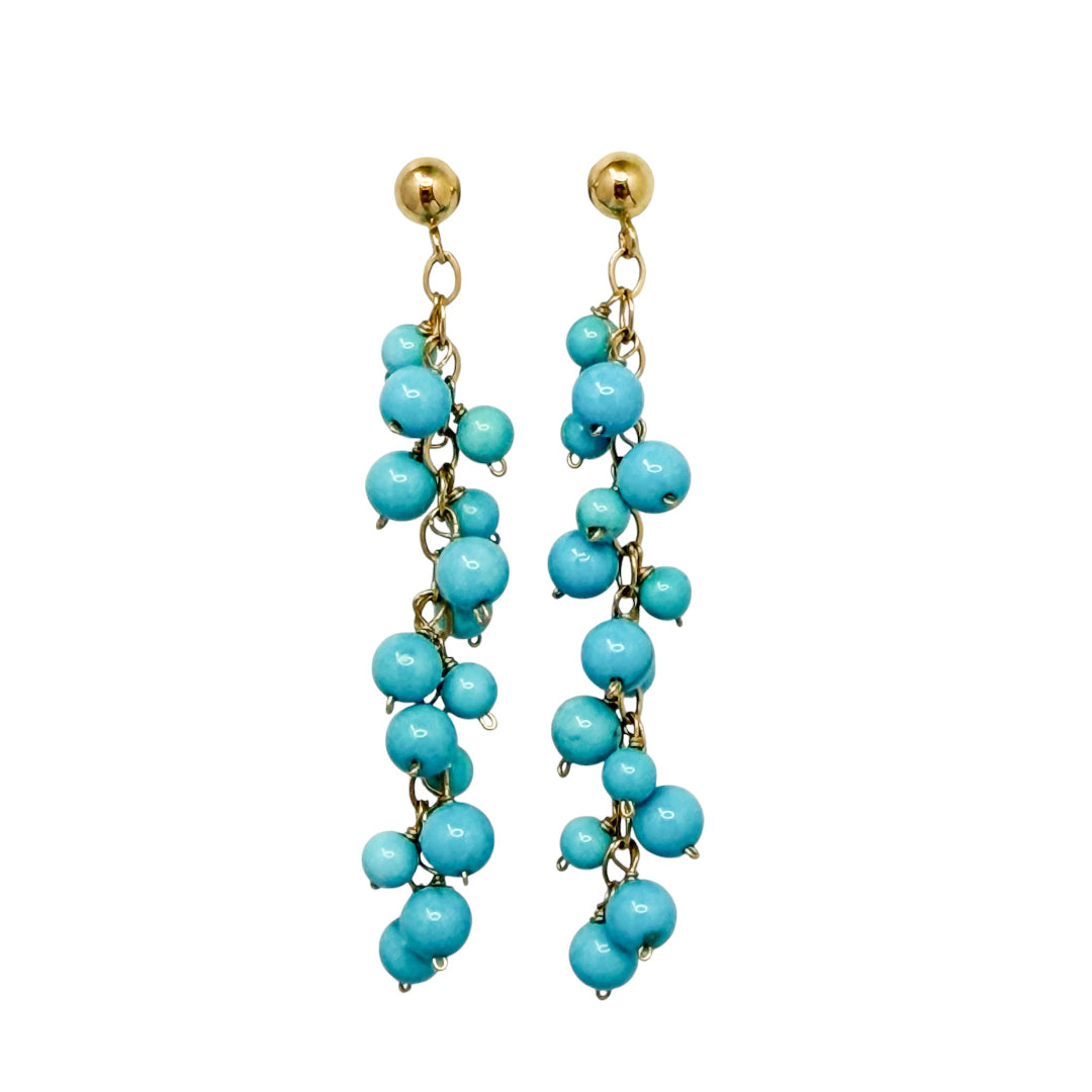 Turquoise beaded earrings set in 14k gold on a white background.