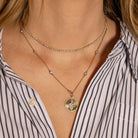 Gold necklace two tone diamond station neckace with a pendant worn by a person in a striped shirt
