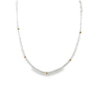 A close-up of a white topaz bead necklace with 14k gold beads on a white background. 